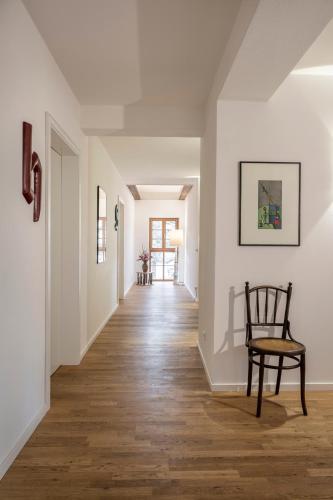 a hallway with a chair and white walls and wood floors at Gasthaus Unterwirt in Fridolfing