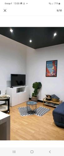 un salon avec une télévision et une table dans l'établissement Chez lolo, à Vichy