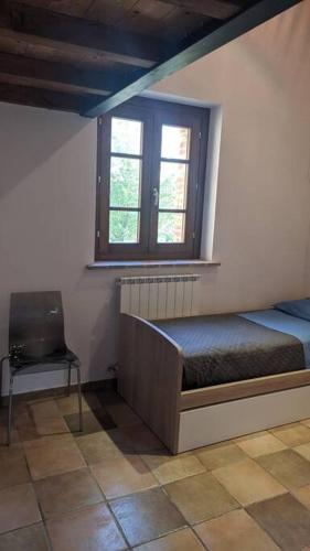 a bedroom with a bed and a window and a chair at Casa nella campagna Umbra in San Terenziano