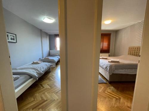 a room with three beds in a room with a hallway at Idealapartments LLC 8 in Pristina
