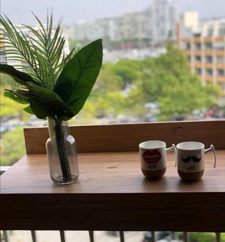 deux tasses à café et un vase avec une plante sur une table dans l'établissement Studio Cosy climatisé Carnon Plage, à Carnon-Plage