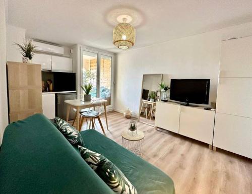 un salon avec un canapé vert et une cuisine dans l'établissement Studio Cosy climatisé Carnon Plage, à Carnon-Plage