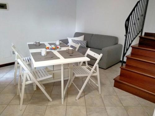 Casa Angelina في غرادو: طاولة بيضاء وكراسي في غرفة معيشة مع أريكة