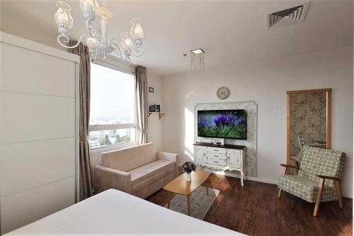 a living room with a couch and a tv at Casa Boutique Hotel in Nahariyya
