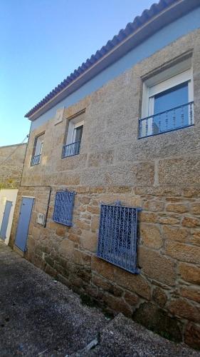 um edifício de tijolos com portas e janelas azuis em Casa O Castriño em Cambados