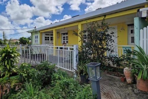 a yellow house with a white fence in front of it at Villa MARICO in Ducos