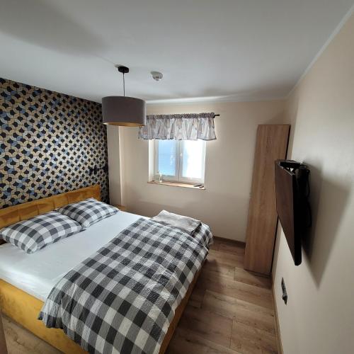 a bedroom with a bed with a checkered blanket and a window at Apartament Łomnicka 59 in Jelenia Góra