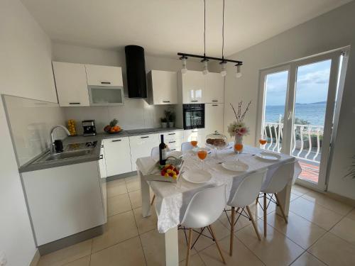 eine Küche mit einem Tisch mit weißen Stühlen und Meerblick in der Unterkunft Apartment Seaside Orebić in Orebić