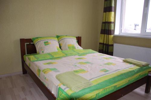 uma cama com um edredão verde e branco e almofadas em Dalekobiynyk em Uzyn