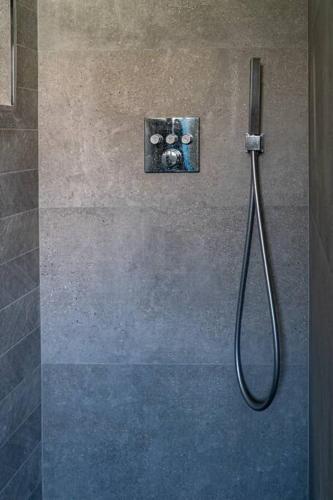 une douche avec un tuyau fixé à un mur dans l'établissement Villa Bella Vista - Contemporary villa with pool and dominant views, à Saint-Gély-du-Fesc