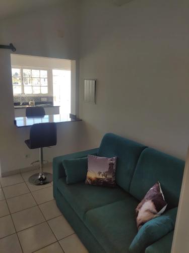 a living room with a green couch with two pillows at Nunes Apartments in Mexilhoeira da Carregacao