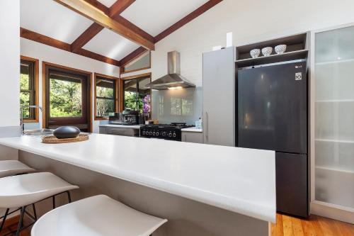uma cozinha com um balcão branco e um frigorífico preto em Hinterland family getaway em Maleny