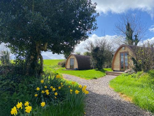 a small cabin in the middle of a garden with yellow flowers at Farmyard Lane Glamping in Killarney