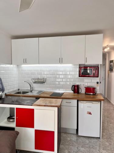 eine Küche mit weißen Schränken und roten und weißen Geräten in der Unterkunft Atlantico in Calpe
