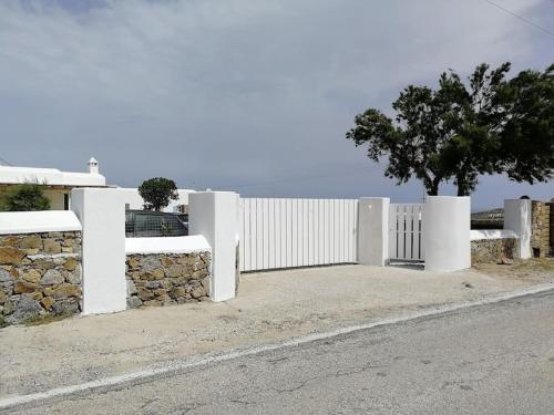 a white fence with a tree next to a street at Blue Waves home Mykonos in Kalo Livadi