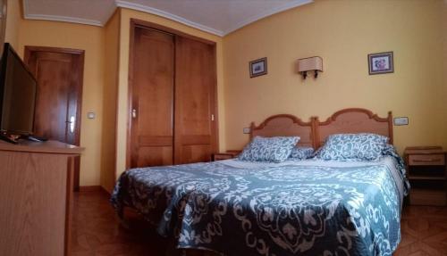 um quarto com uma cama com um edredão azul e uma televisão em Alojamientos Prada em Ballota