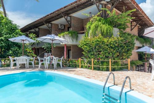 a villa with a swimming pool and patio furniture at Pousada Barra Sol in Barra de São Miguel