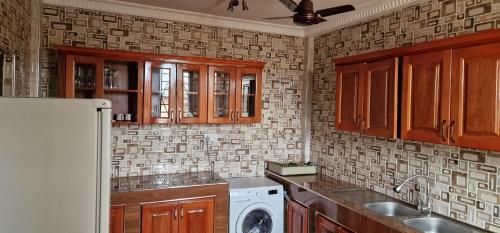 a kitchen with wooden cabinets and a washer and dryer at OKF OBOUBA APARTMENT in Kumasi