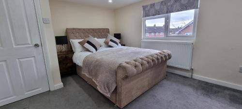 a bedroom with a large bed and a window at Spacious Large House - Very close to M1 - Walking distance to L&D Hospital - Contractor Friendly - Large groups in Luton