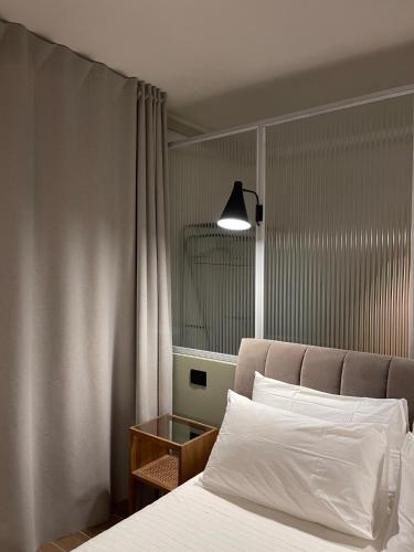 a bedroom with a bed with white sheets and a lamp at Raha Suites in Syracuse