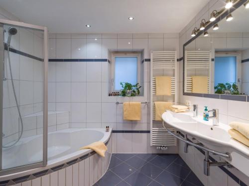 a bathroom with a tub and two sinks and a shower at Blaiken Appartements in Scheffau am Wilden Kaiser in Scheffau am Wilden Kaiser