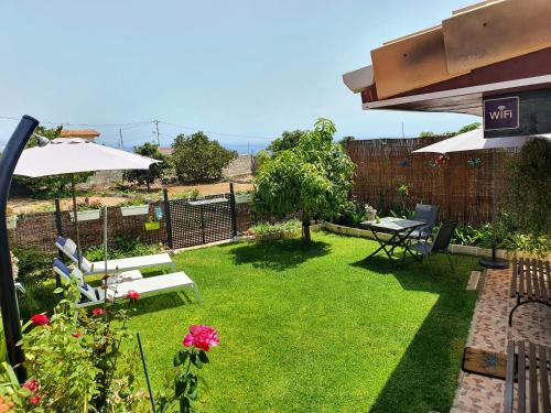 a garden with a table and chairs and an umbrella at Casa Rural Eneida in Chiquenge