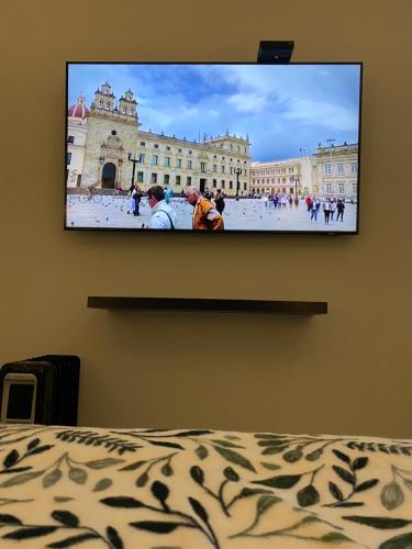 a flat screen tv hanging on a wall above a bed at Cal Bed & Breakfast in Bogotá
