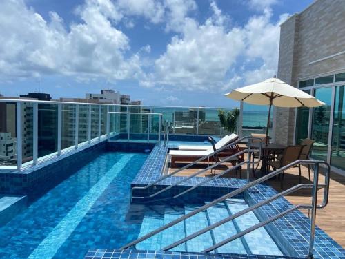 uma piscina no topo de um edifício com um guarda-chuva em Promenade II Ap 508 PONTA VERDE - MACEIÓ em Maceió