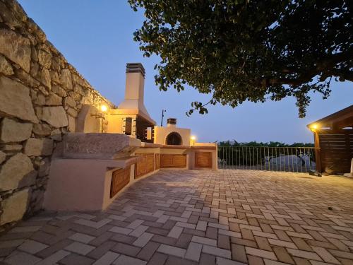 a house with a stone wall and a brick driveway at ONOMY Country House Vathypetro in Archanes