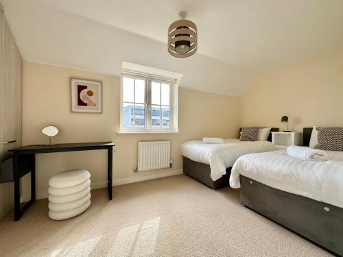 Un dormitorio con dos camas y un escritorio y una ventana. en Homely 3 bedroomed House in Bicester, en Bicester