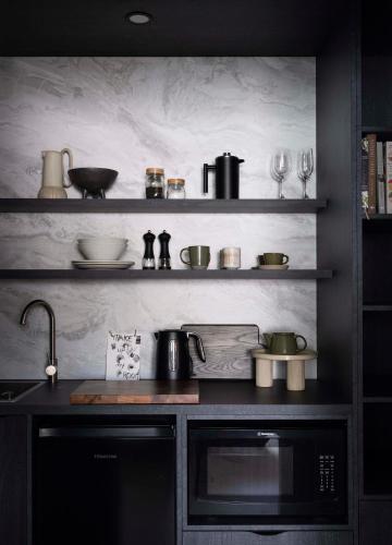 a kitchen with a sink and shelves with pots and pans at Tallowwood House Luxury Bed & Breakfast in Port Macquarie