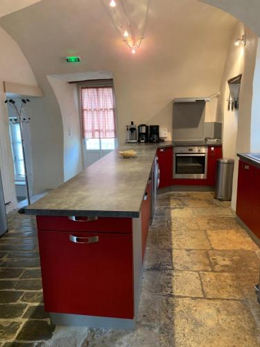 a kitchen with red cabinets and a counter top at Gîte l'oustal de la fontaine Grand Causses et Gorges du Tarn in Mostuéjouls