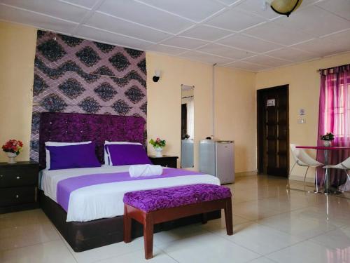 a bedroom with a large bed with purple sheets at ZUNOX GUEST HOUSE in Freetown