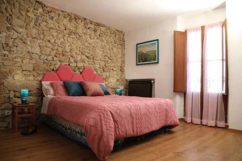 1 dormitorio con pared de piedra y cama roja en Sally's House en San Gemini