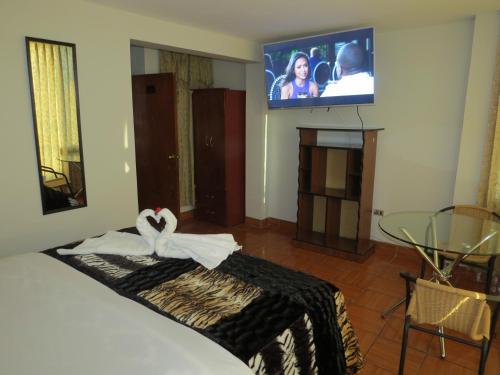 a bedroom with a bed with a tv on the wall at Hospedaje El Rinconcito in Jauja