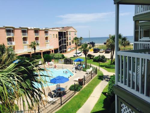 a view of a pool and the ocean from a balcony at The Victorian Condo/Hotel in Galveston