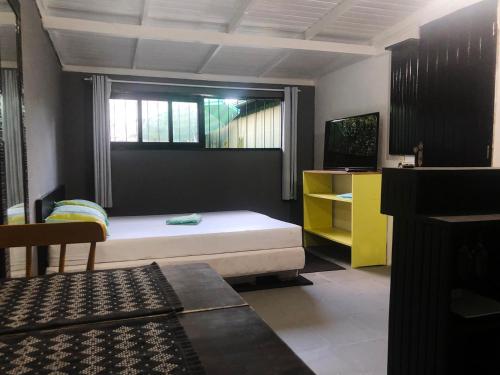 a bedroom with a bed and a window and a tv at Studio Centro Garopaba in Garopaba