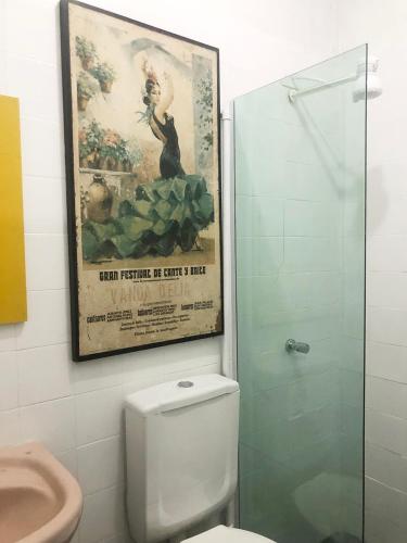 a bathroom with a picture on the wall above a toilet at Studio Centro Garopaba in Garopaba