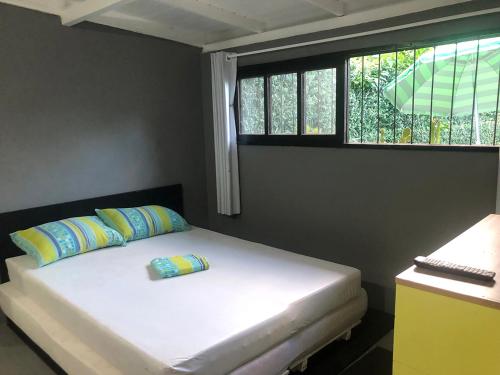 a bedroom with a white bed with pillows and a window at Studio Centro Garopaba in Garopaba
