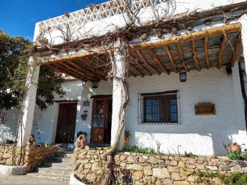 uma casa branca com uma pérgula de madeira em EL RINCON DE YEGEN em Yegen