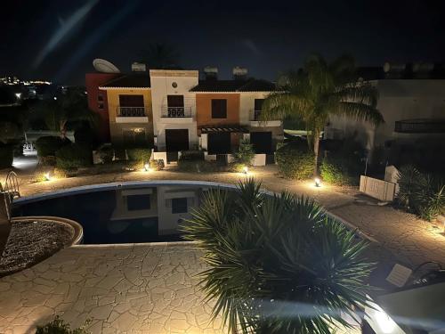 a swimming pool in front of a house at night at Apartament Cosy House with pool, Paphos Pafos,Tombs of Kings in Paphos