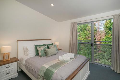 a bedroom with a bed and a large window at Ocean Serenity Apartments Whitianga in Whitianga