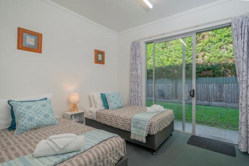 a bedroom with two beds and a window at Ocean Serenity Apartments Whitianga in Whitianga