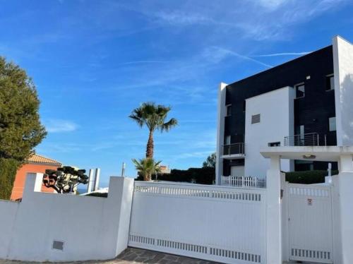 a white fence in front of a house with a palm tree at Villa en Oropesa in Oropesa del Mar