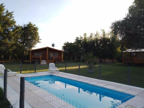 a swimming pool with two chairs and a house at CABAÑAS LAS ACACIAS in Colonia Las Rosas