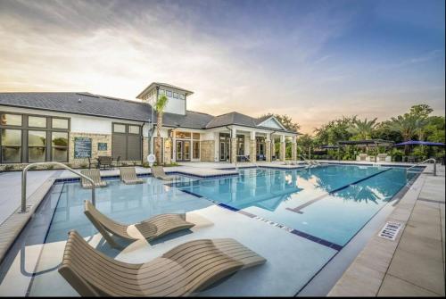 a large swimming pool with chairs in front of a house at Ideal Modern Retreat in Jacksonville
