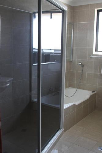 Un baño con ducha, lavabo y bañera. en Bennett's Bliss - Soak in Breathtaking Ocean View, en Forster