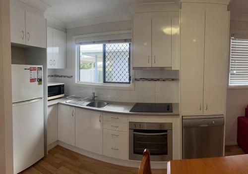 a kitchen with white cabinets and a sink and a window at Pete's Place Roma in Roma