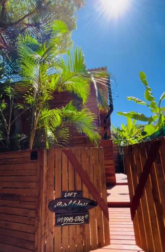 a sign on a wooden fence with palm trees at Surfway Ilha do Mel Lofts in Ilha do Mel