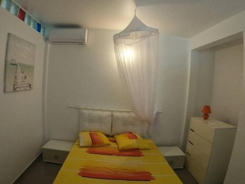 um pequeno quarto com uma cama com um cobertor amarelo em Le colibri voyageur em Sans Pareil